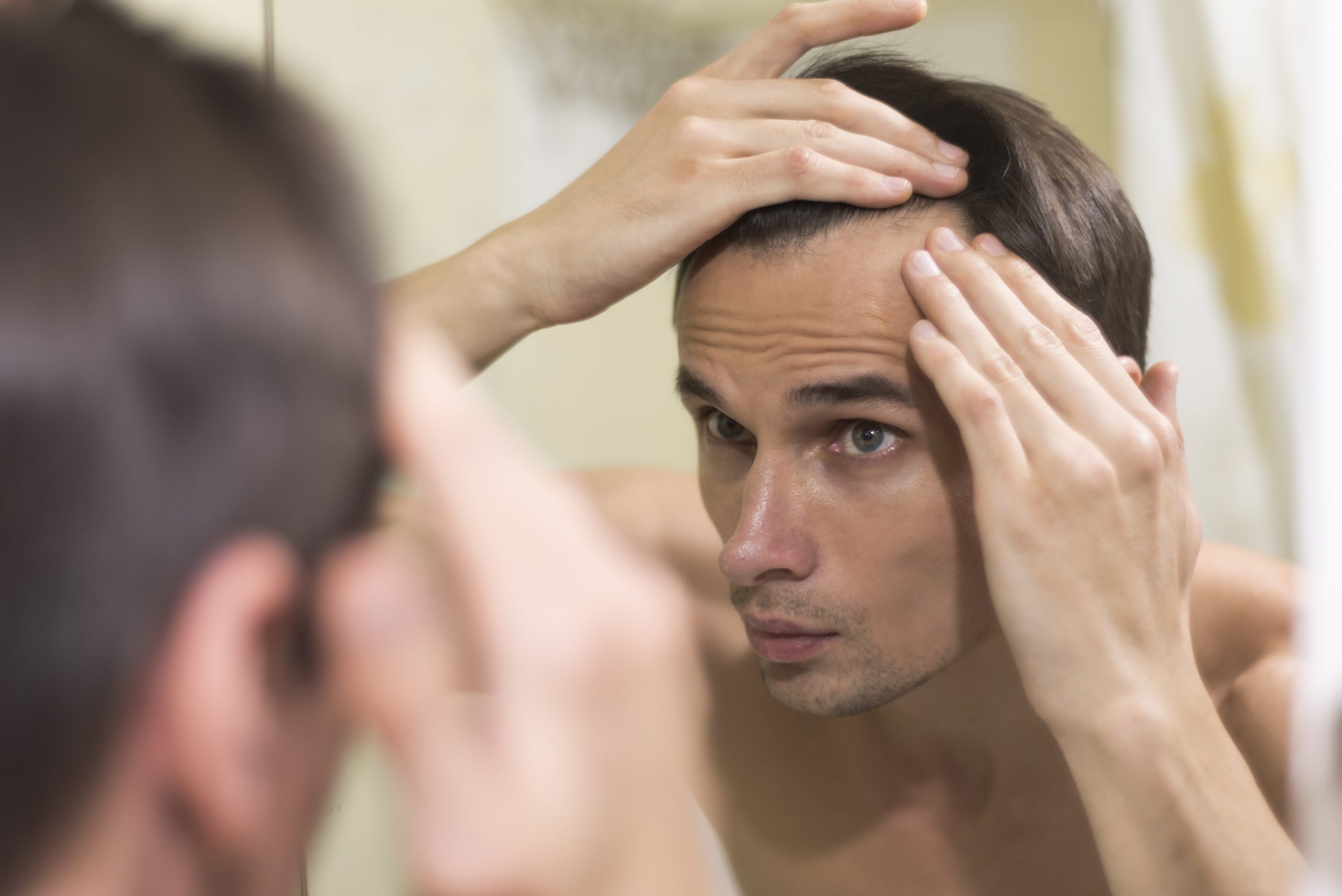 gros-plan-homme-cheveux-toilettage homme regardant dans un miroir les début de sa chute de cheveux