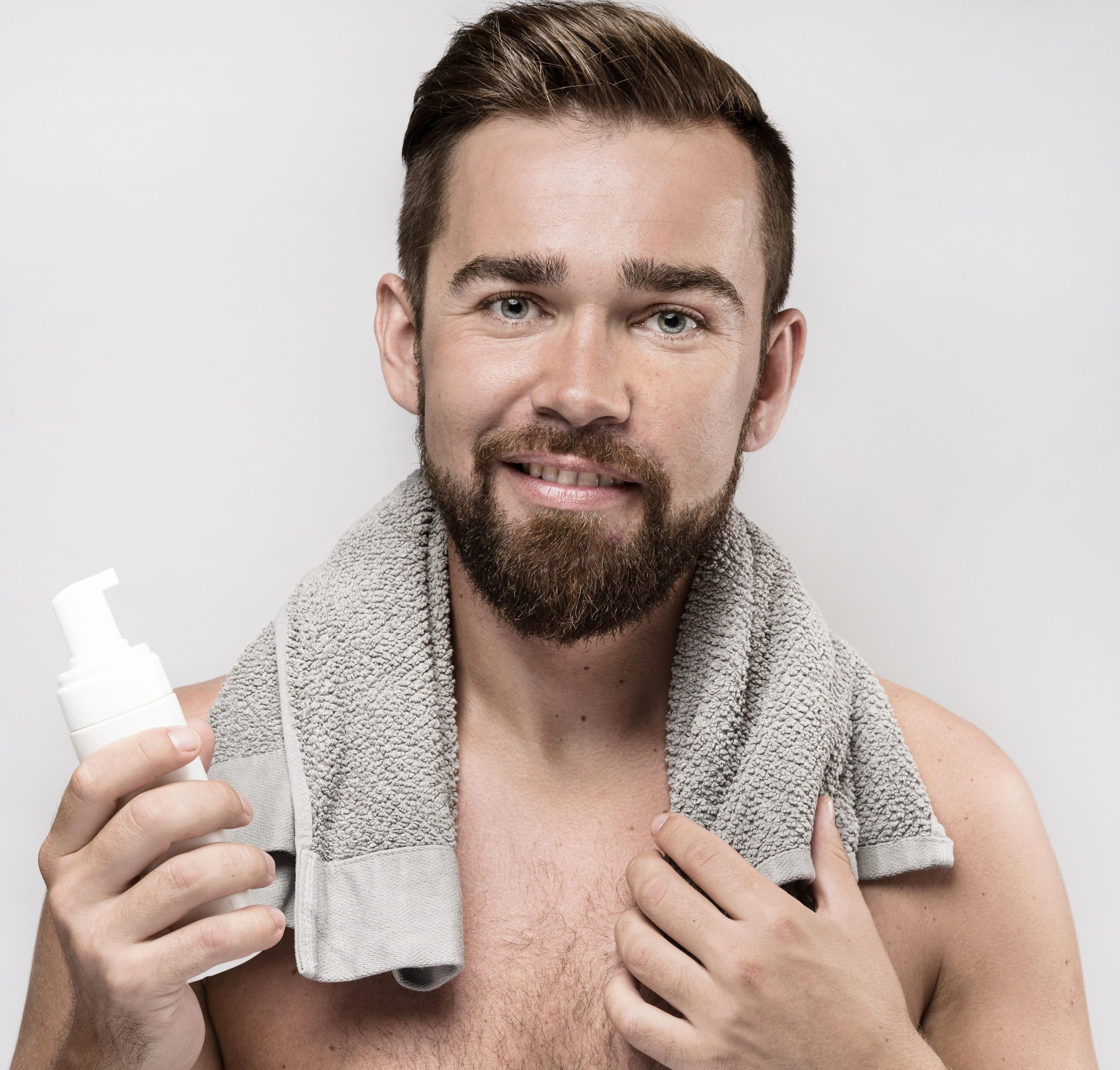 homme-tenant-une-bouteille-de-creme-a-raser Homme torse nu avec une serviette autour de cou et une bouteille a la main