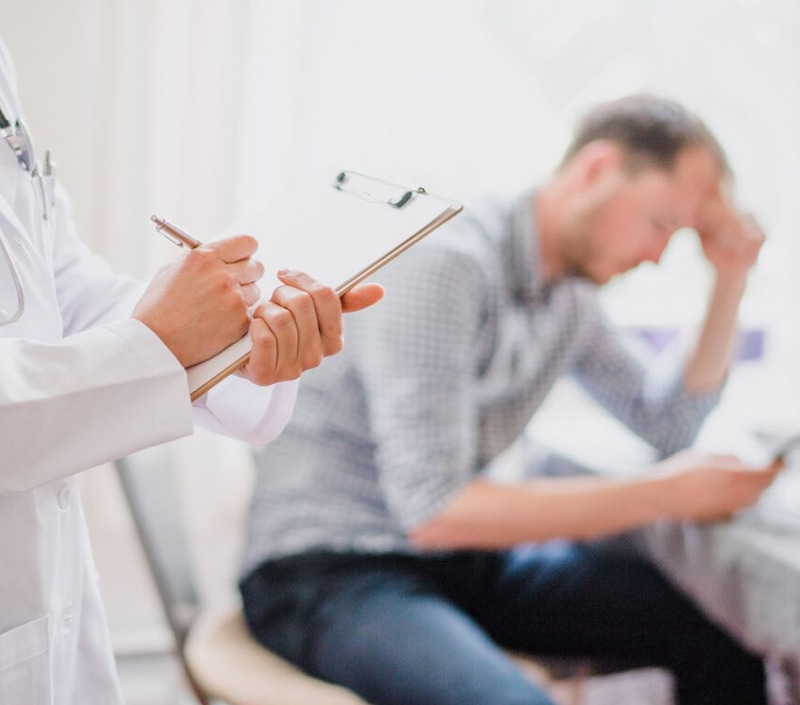 img-8 image d'un homme devant un medecin qui tient un bloc note et un stylo dans ses mains